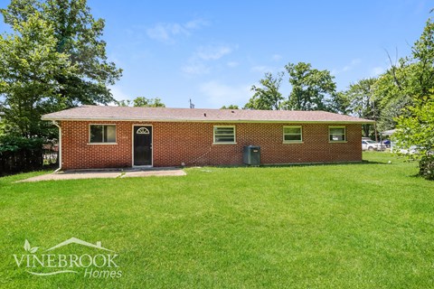 the front of a brick house with a green lawn